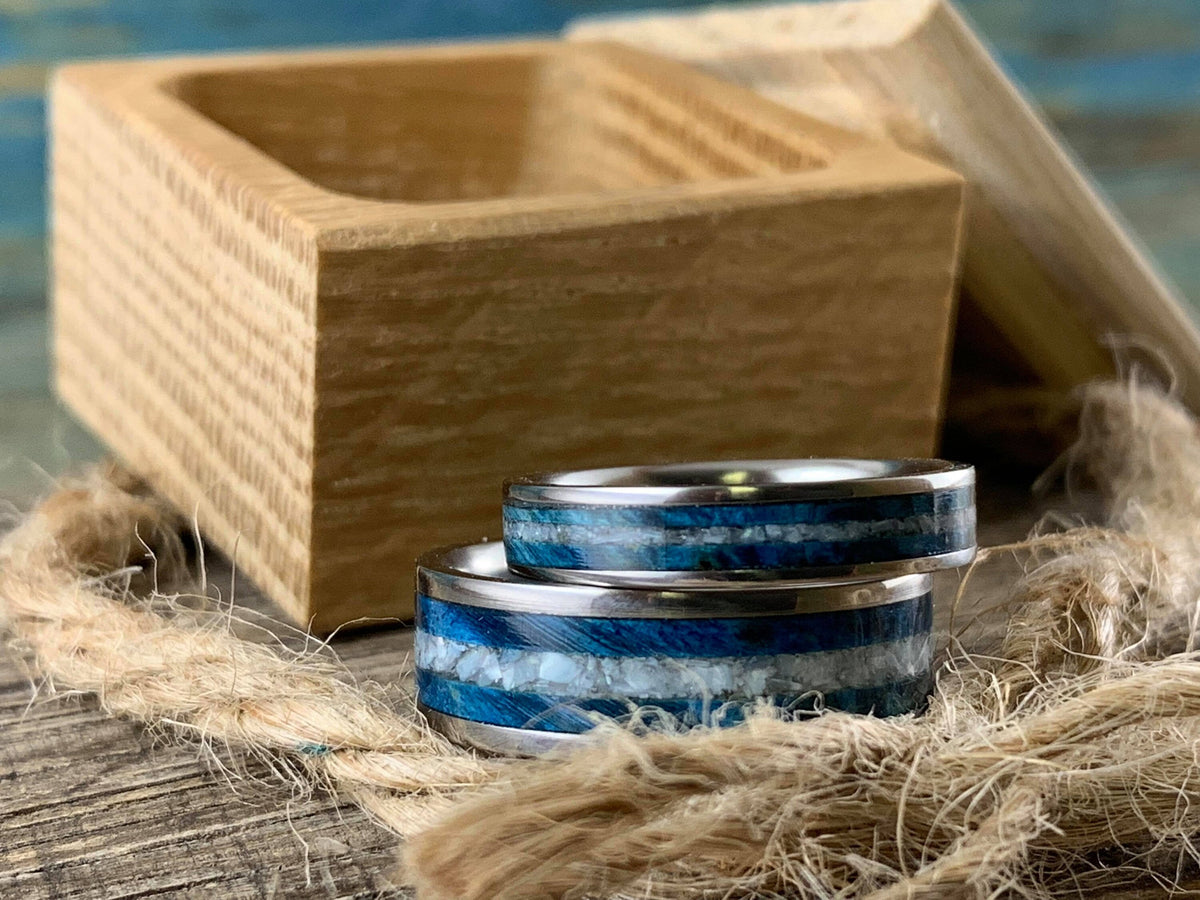 Matching titanium wedding bands with blue wood and pearl inlays for him and her, designed by RobandLean's rings.