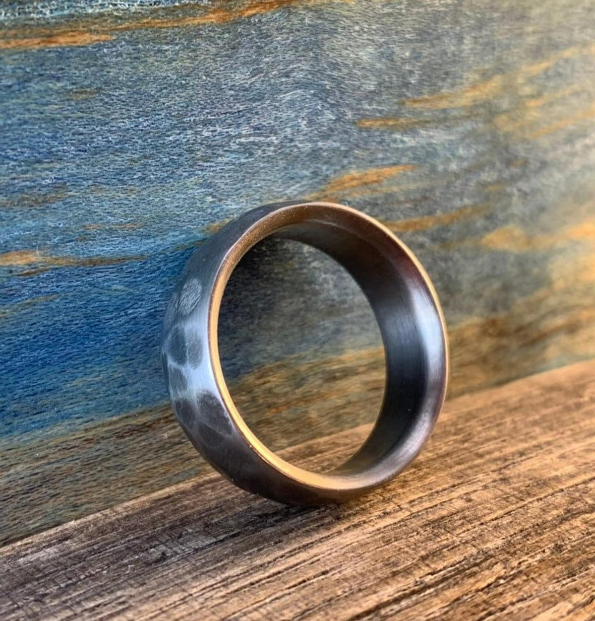 A three-quarters angle view of the metal ring standing on edge, highlighting its textured exterior and hollow interior. __etsy:8394273578