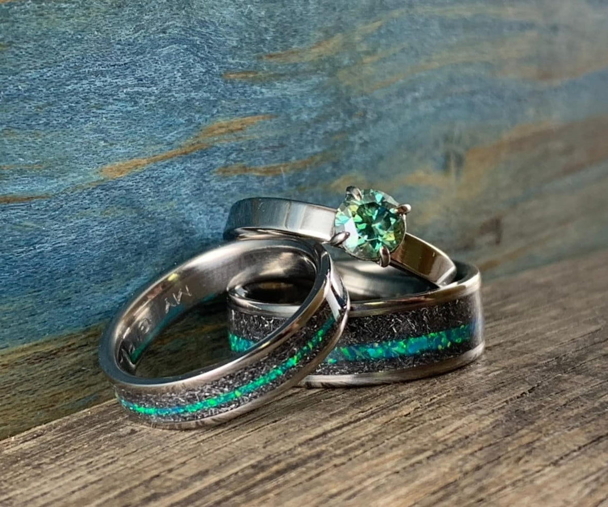 Close-up of three custom rings, including two meteorite and teal opal bands paired with a teal moissanite solitaire engagement ring. __etsy:8377671196