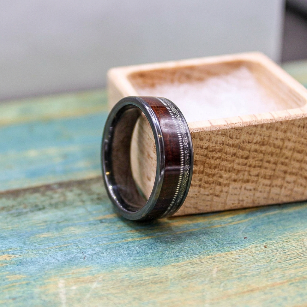 RobandLean's black titanium wedding band with rosewood, meteorite inlay, and guitar string detail, rustic presentation.