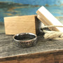 Titanium wedding band featuring custom composite inlay of meteorite, dinosaur bone, and metal flakes