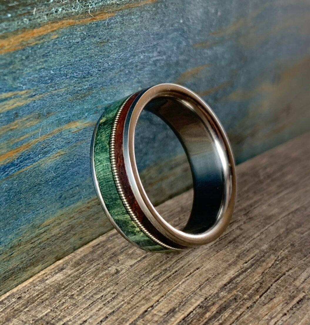 Ring with green wood, Guitar String and Rosewood inlay on a wooden surface