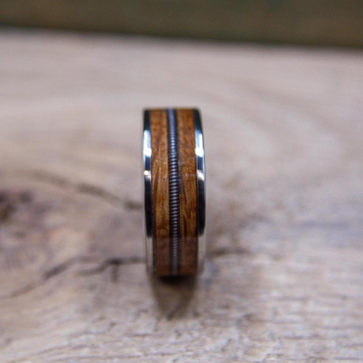 Detailed view of guitar string and whiskey barrel wood inlay in titanium ring