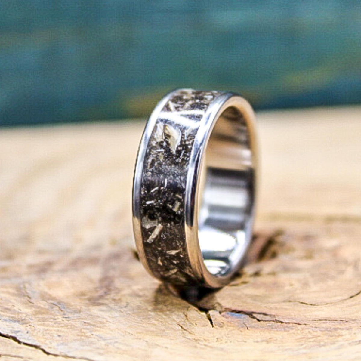 Handmade fossil wedding band with megalodon tooth inlay on wooden surface