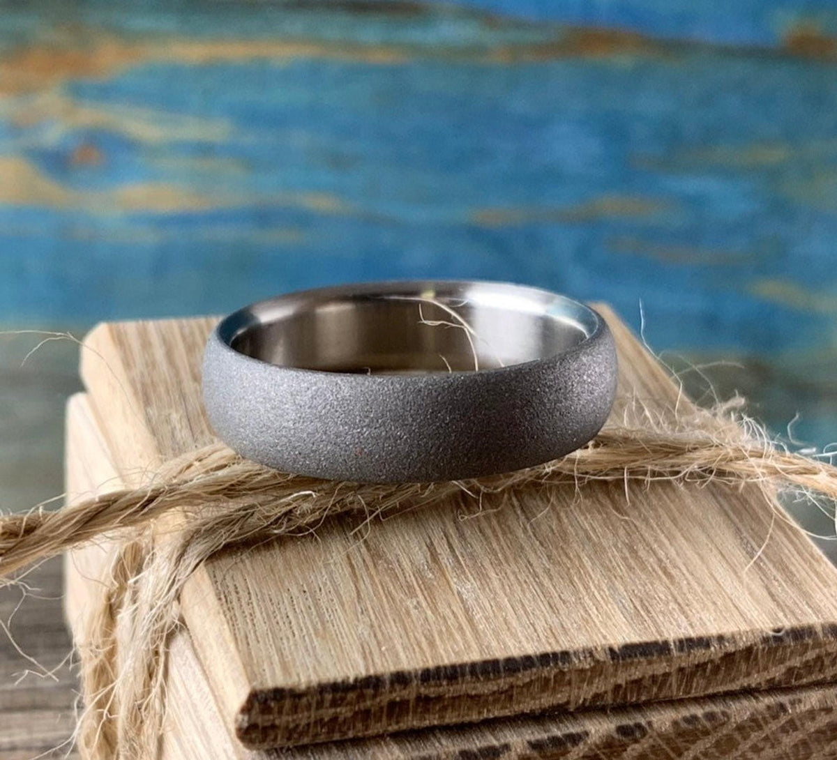 Custom sandblasted titanium wedding band on handmade wooden ring box tied with twine