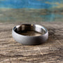 Matte sandblasted titanium wedding band displayed on rustic weathered wood