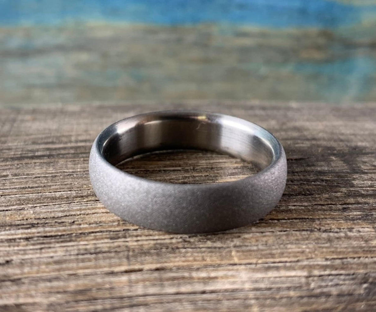 Elevated view of custom sandblasted titanium ring on rustic wooden workshop table