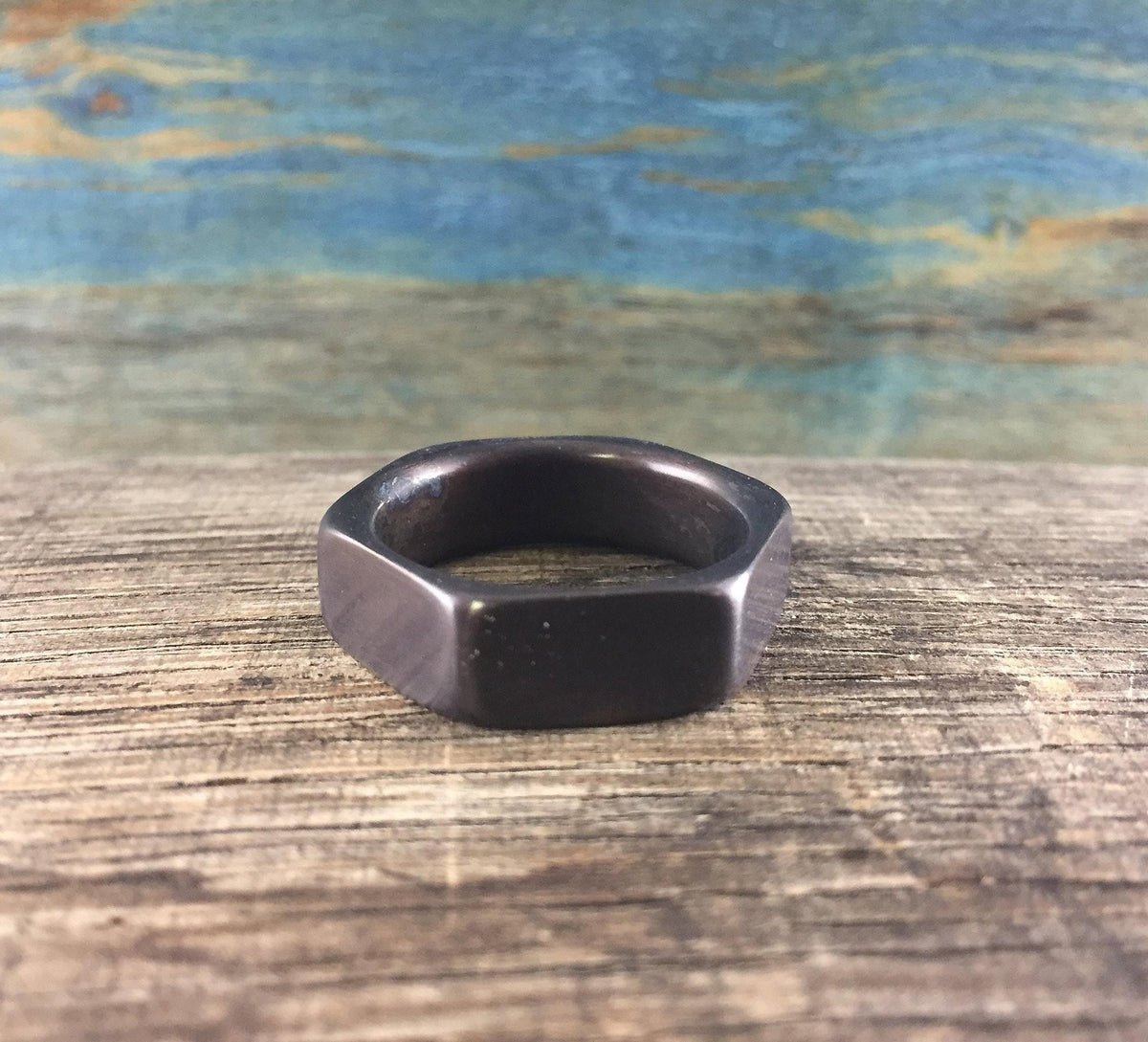 A dark hexagonal ring is centered on a wooden surface, viewed from the front.