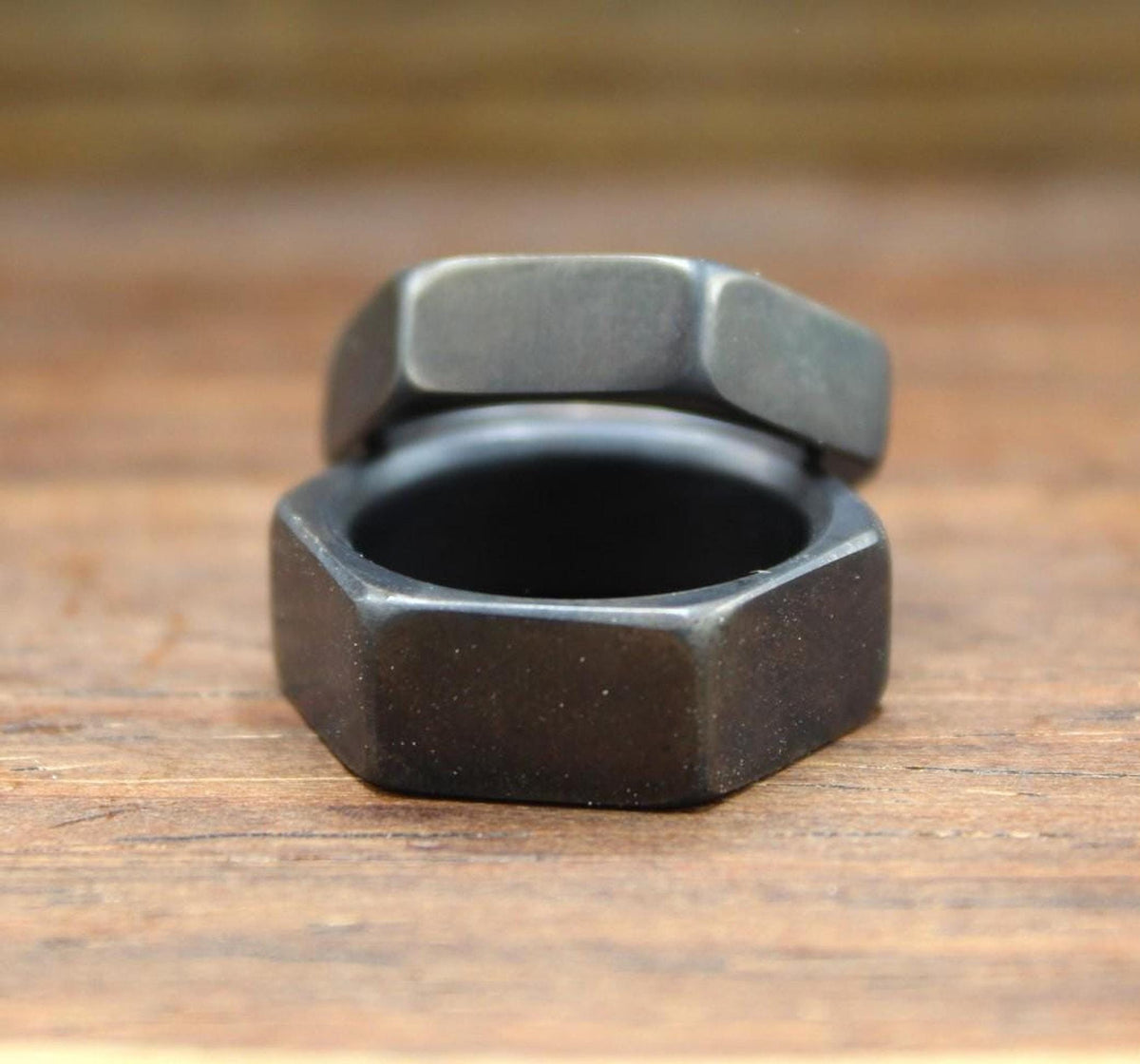 One dark gray hexagonal ring resting on top of another dark gray hexagonal ring, viewed from the front.