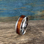 A silver-toned ring with a central ironwood inlay, angled slightly on a wooden surface with a blue and brown background.