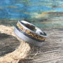 A silver-colored ring with a sandblasted finish and a central band of yellow, orange, and black flecks, rests on a coiled rope.