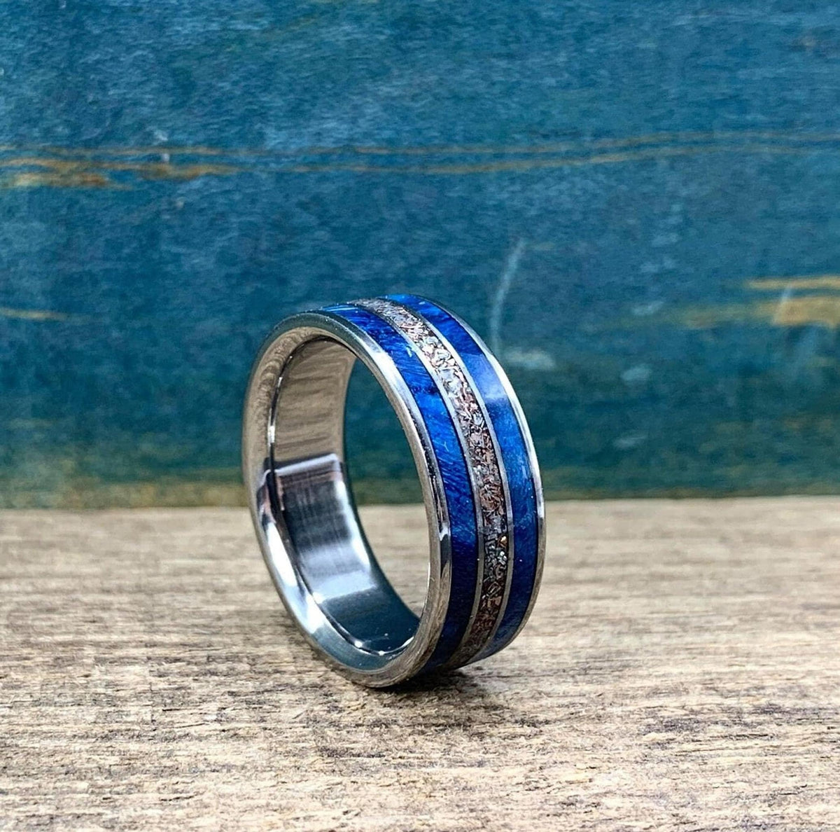 The ring rests upright on a wooden table, angled slightly to display its textured central channel.