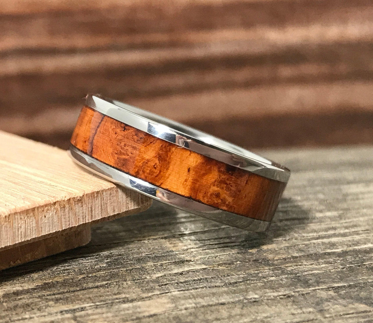 A metal and wood ring rests at an angle on a small piece of wood.