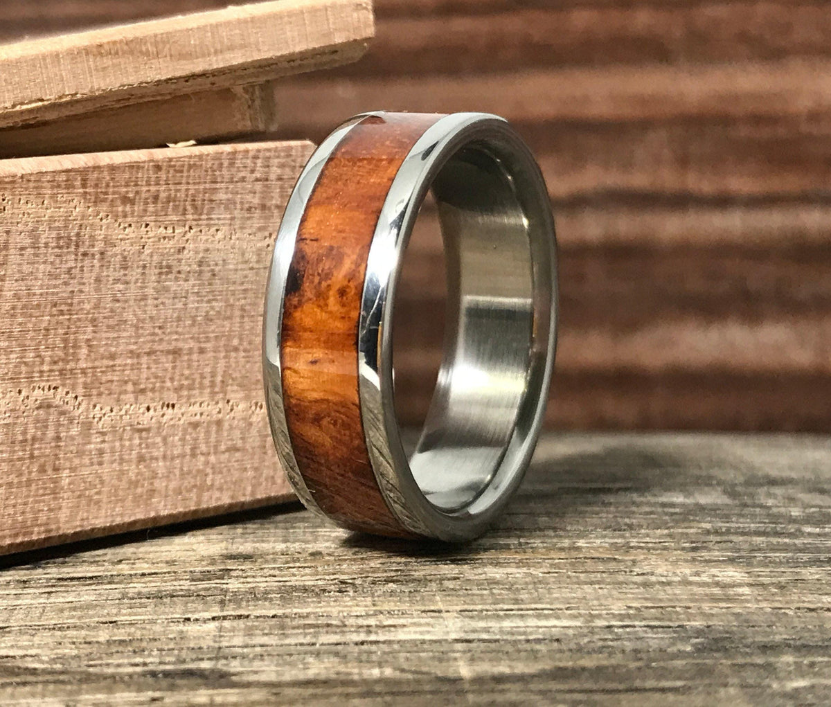 A metal ring with a wood inlay stands upright beside a small wooden box.