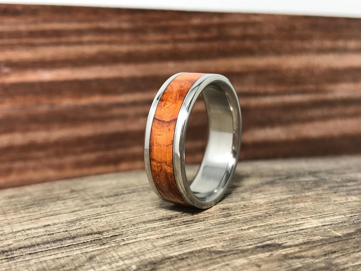 A metal ring with a wooden inlay is positioned upright against a dark wood background.