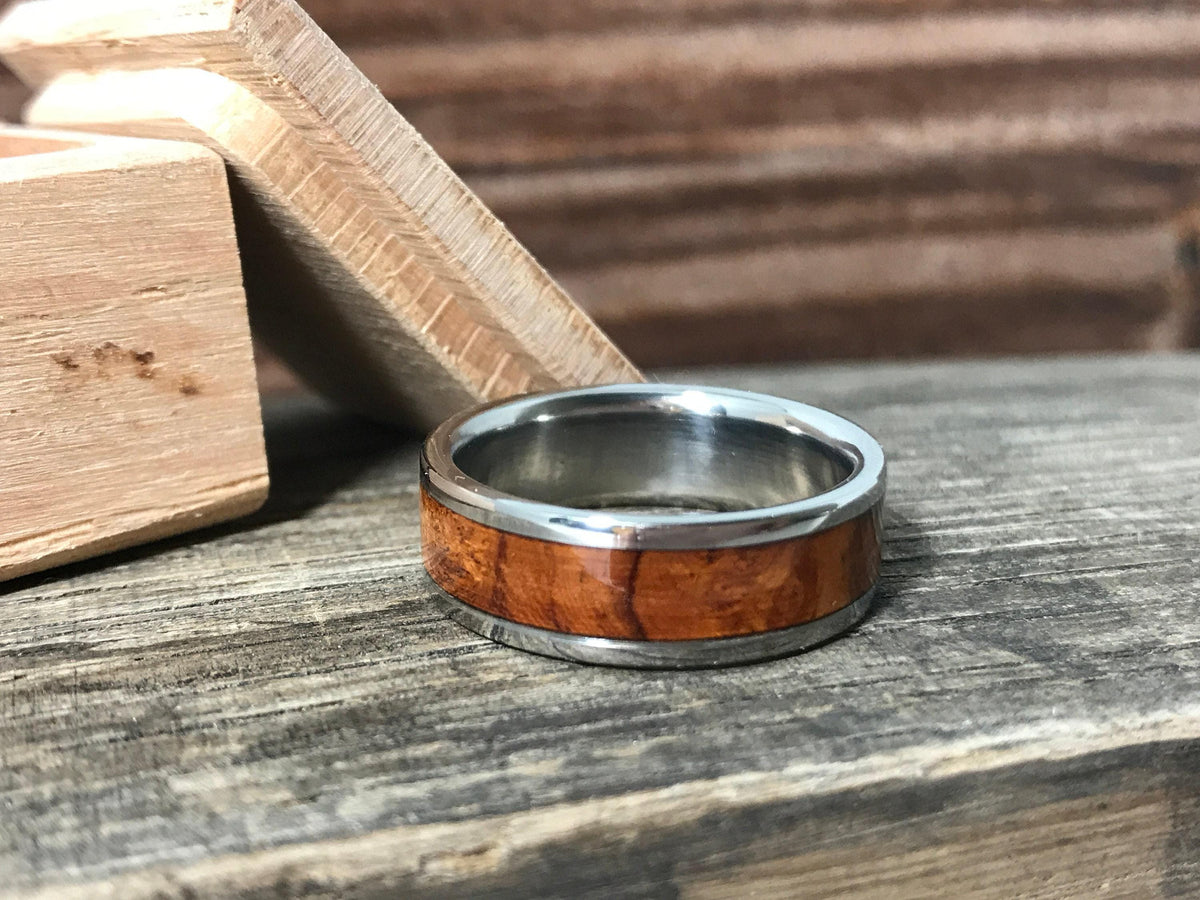 A metal ring with a wood inlay lies flat next to a small wooden box lid.