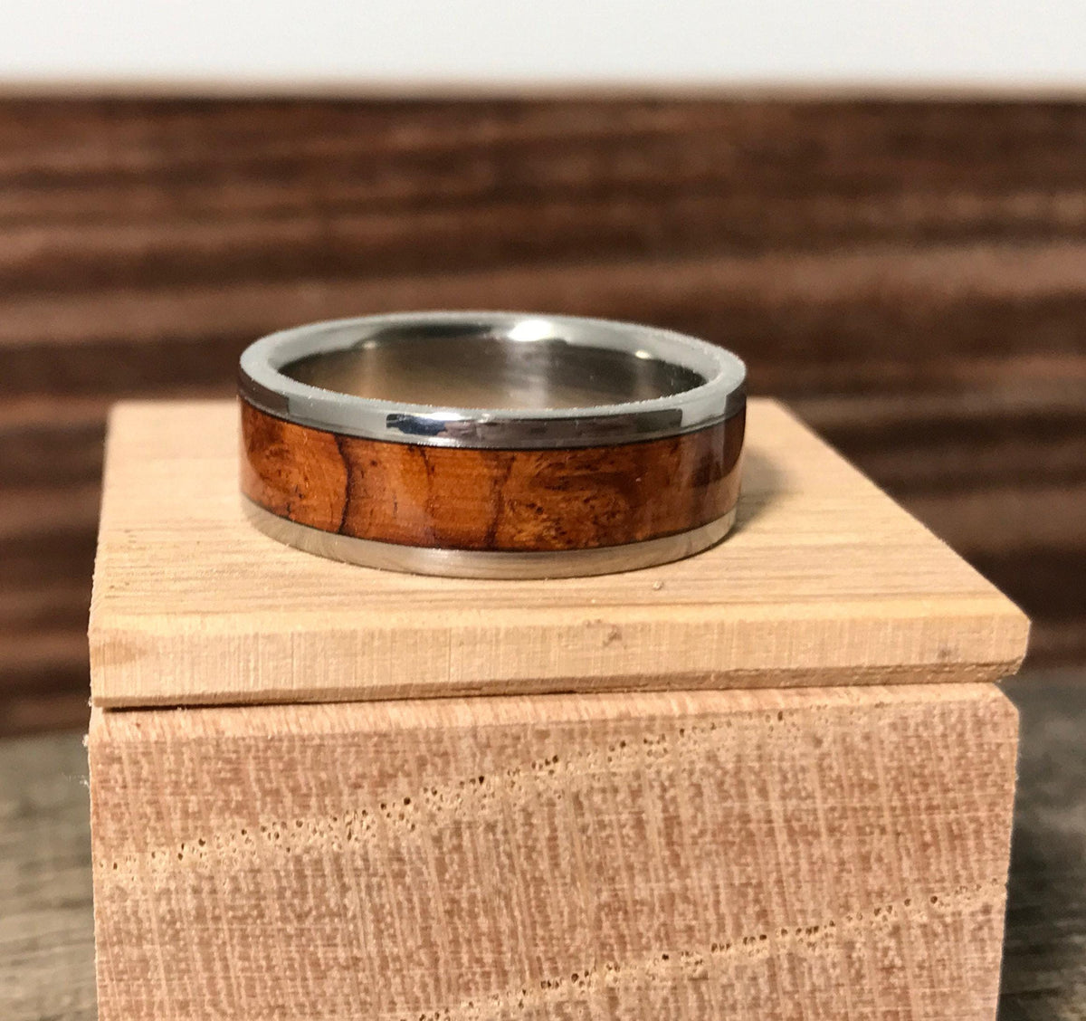 A metal ring with a wooden inlay rests on top of a small wooden block.