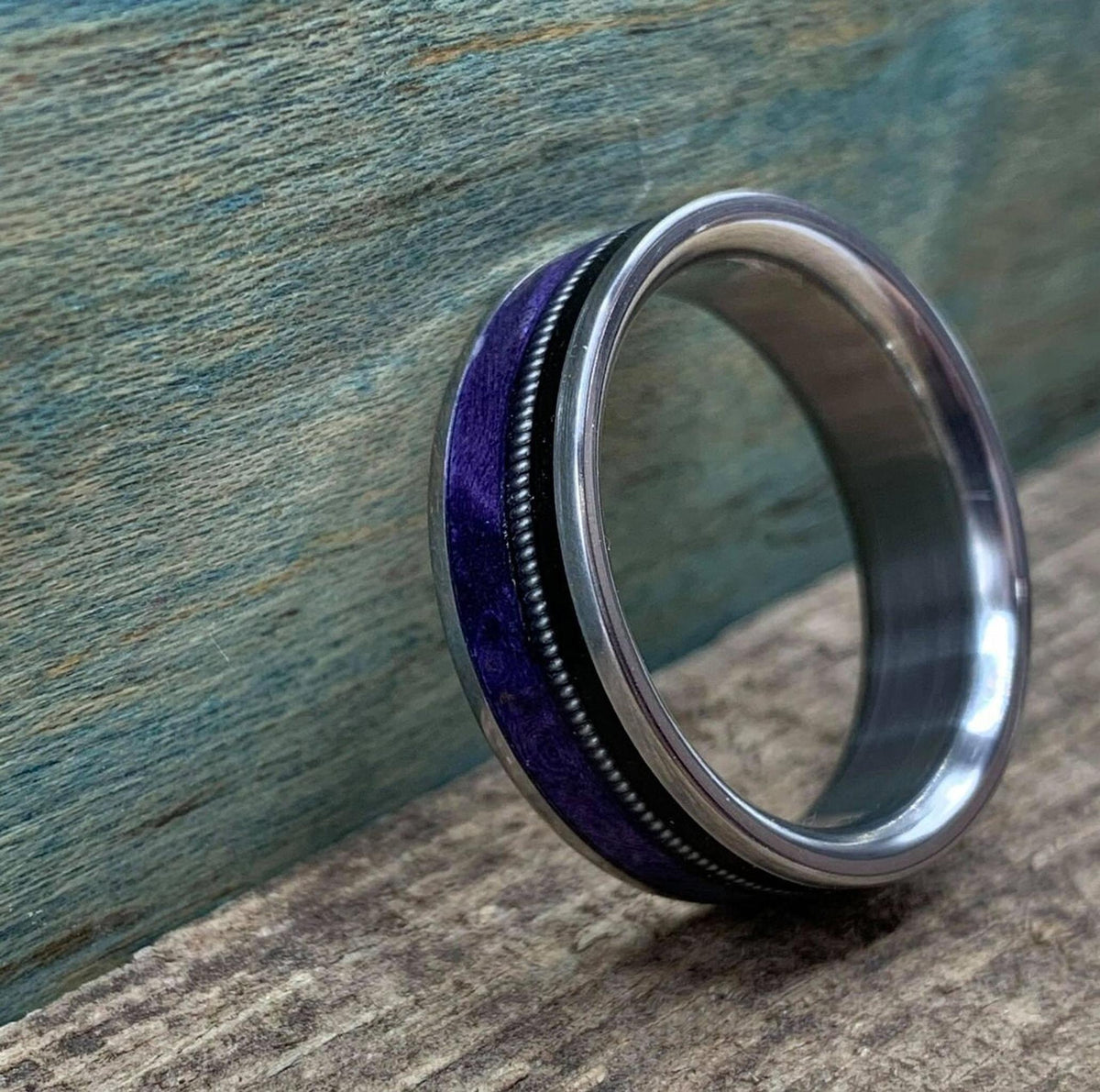 A perspective view of the ring angled against a teal and brown textured backdrop, emphasizing the glossy finish.
