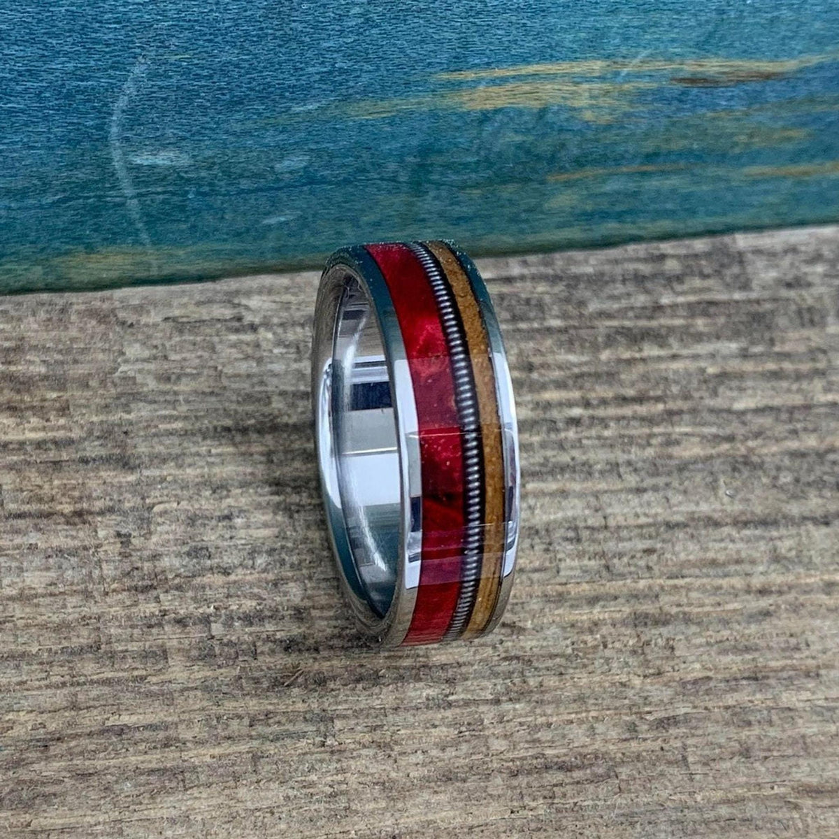 A close-up shot of the ring angled upright, emphasizing the contrasting textures of the polished metal, wood grains, and central coiled wire.