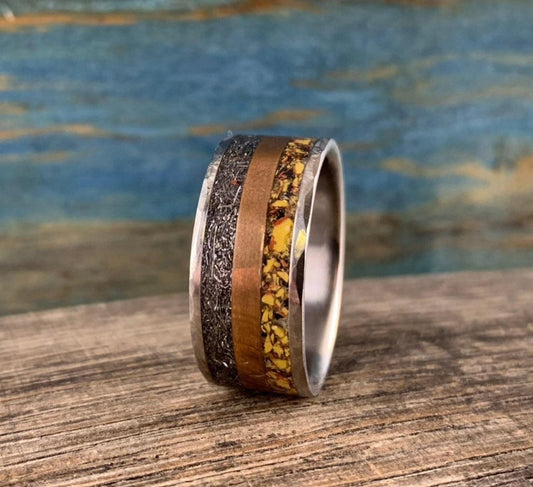 A silver-colored ring with a hammered texture on the outer edges, a smooth copper-colored band, and a textured yellow-orange band in the center.