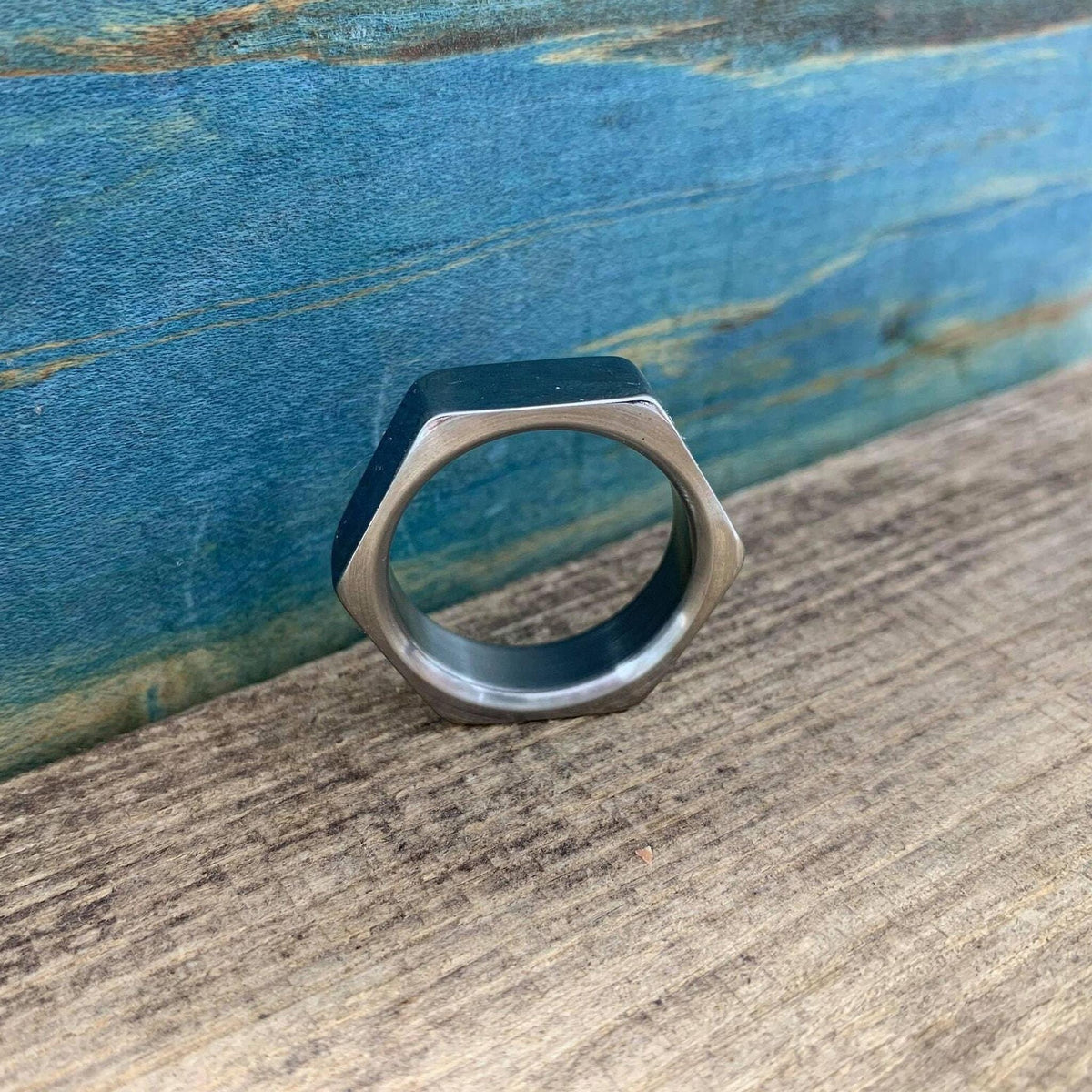 A front view of the metal hexagonal hardware nut ring on a rustic wooden ledge.