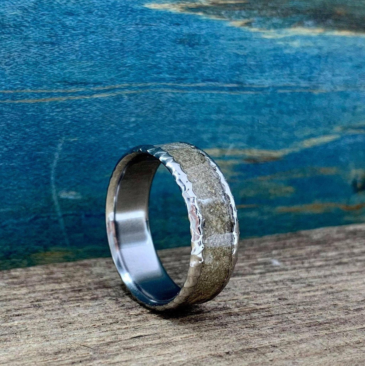 A slightly angled view of the titanium and concrete band resting on a textured wooden plank.
