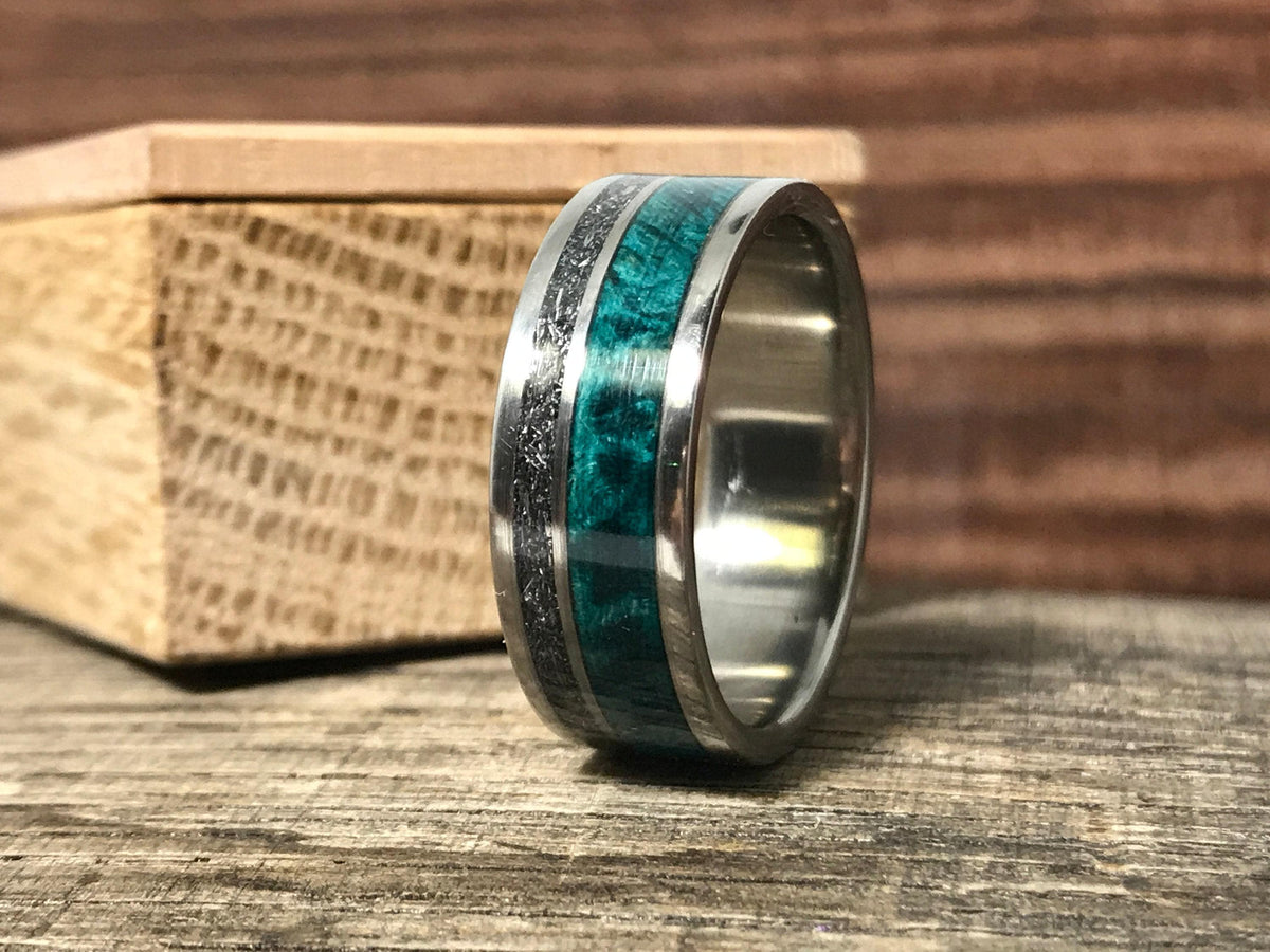 The ring sits upright on a wooden surface in front of a small wooden block, showing the interior finish and detailed outer bands.
