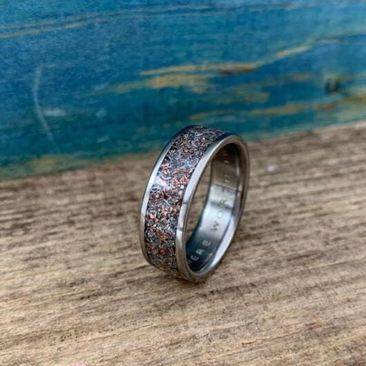 A close-up of the metal band showing engraved text on the inner surface and the granular inlay.