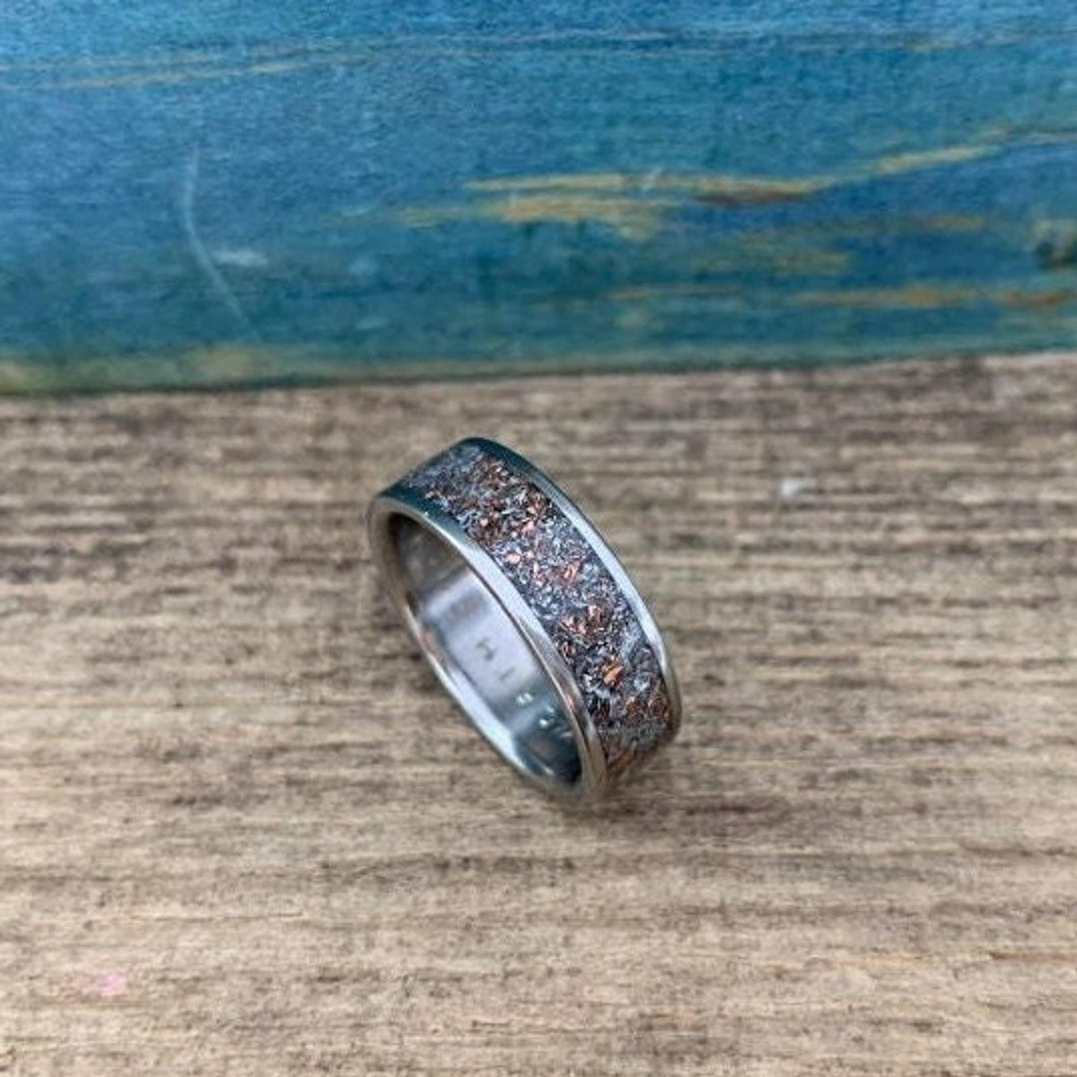 A straight-on view of the ring, displaying its metallic edges and flake-filled center inlay.