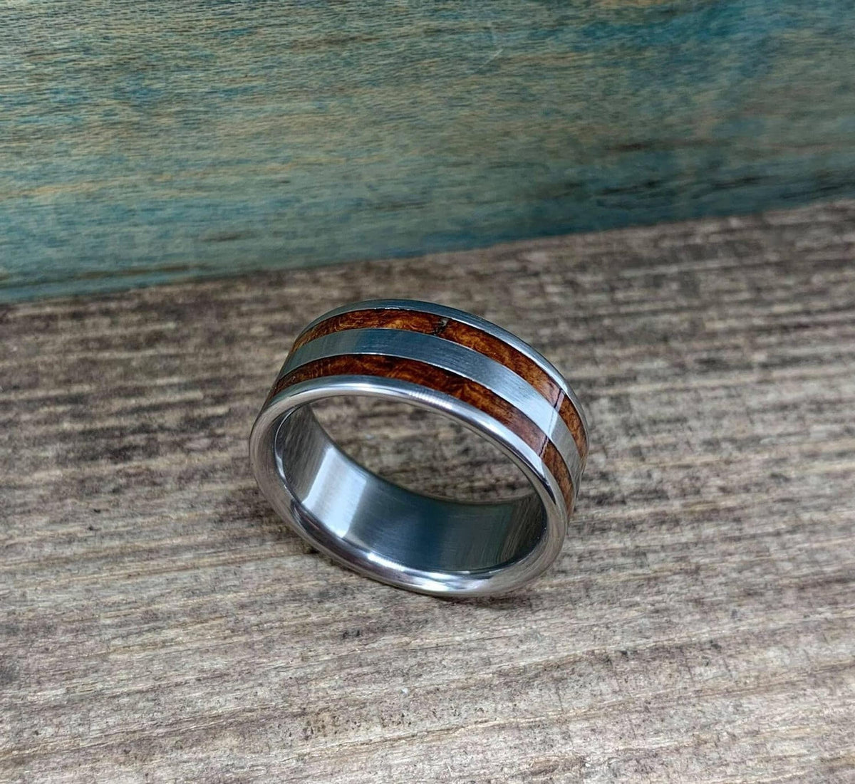The ring resting flat with the wood inlay facing upward on the wooden background.