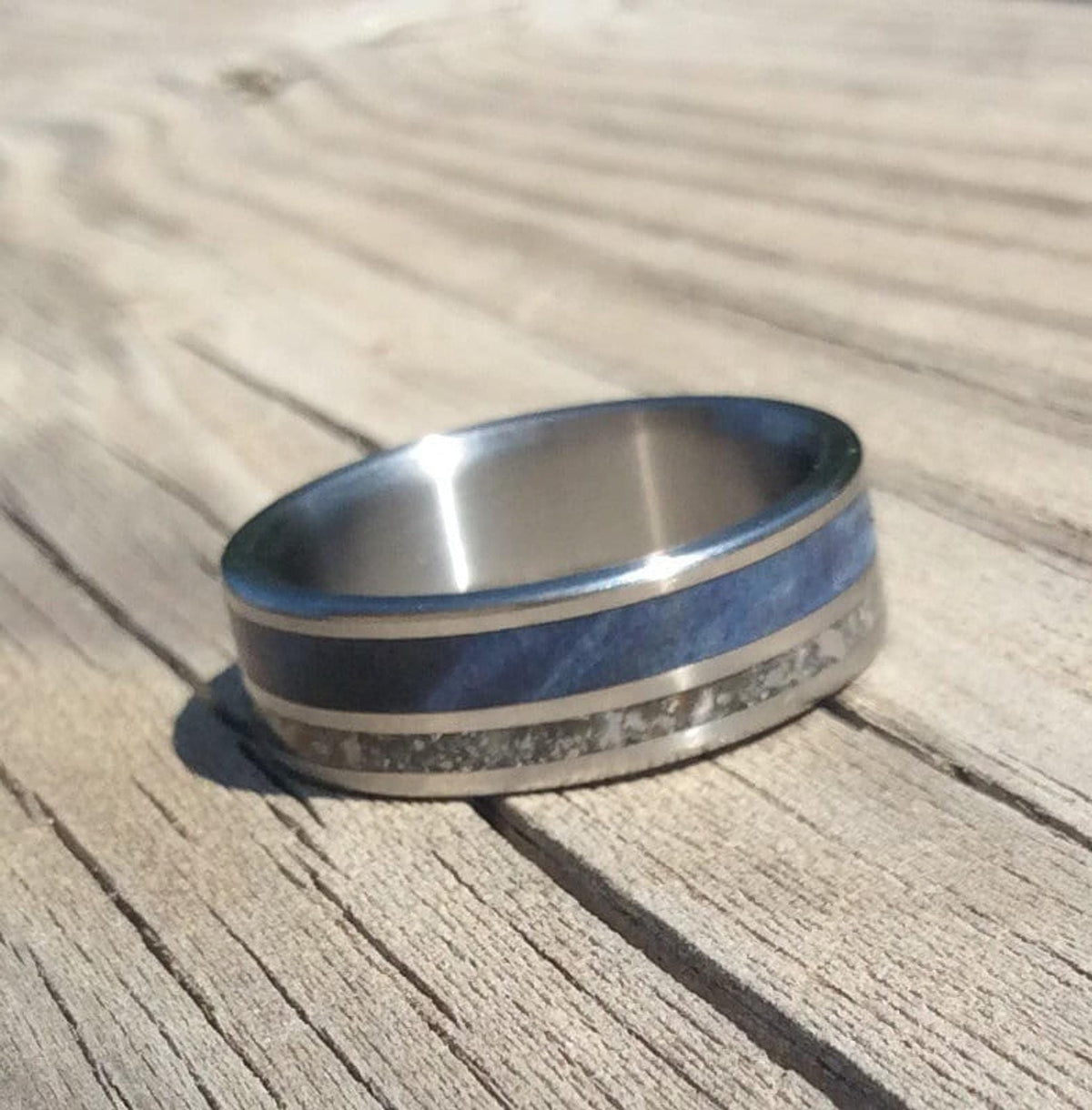 The titanium ring resting flat on a rustic wooden board, showing the band width.