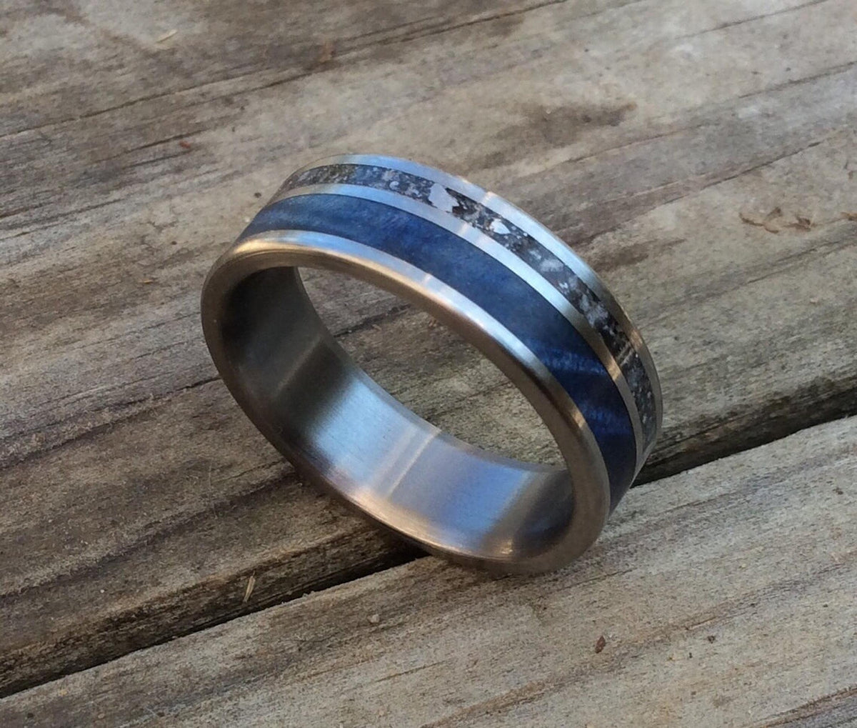 A close-up view of the titanium ring tilted on a textured wooden background.
