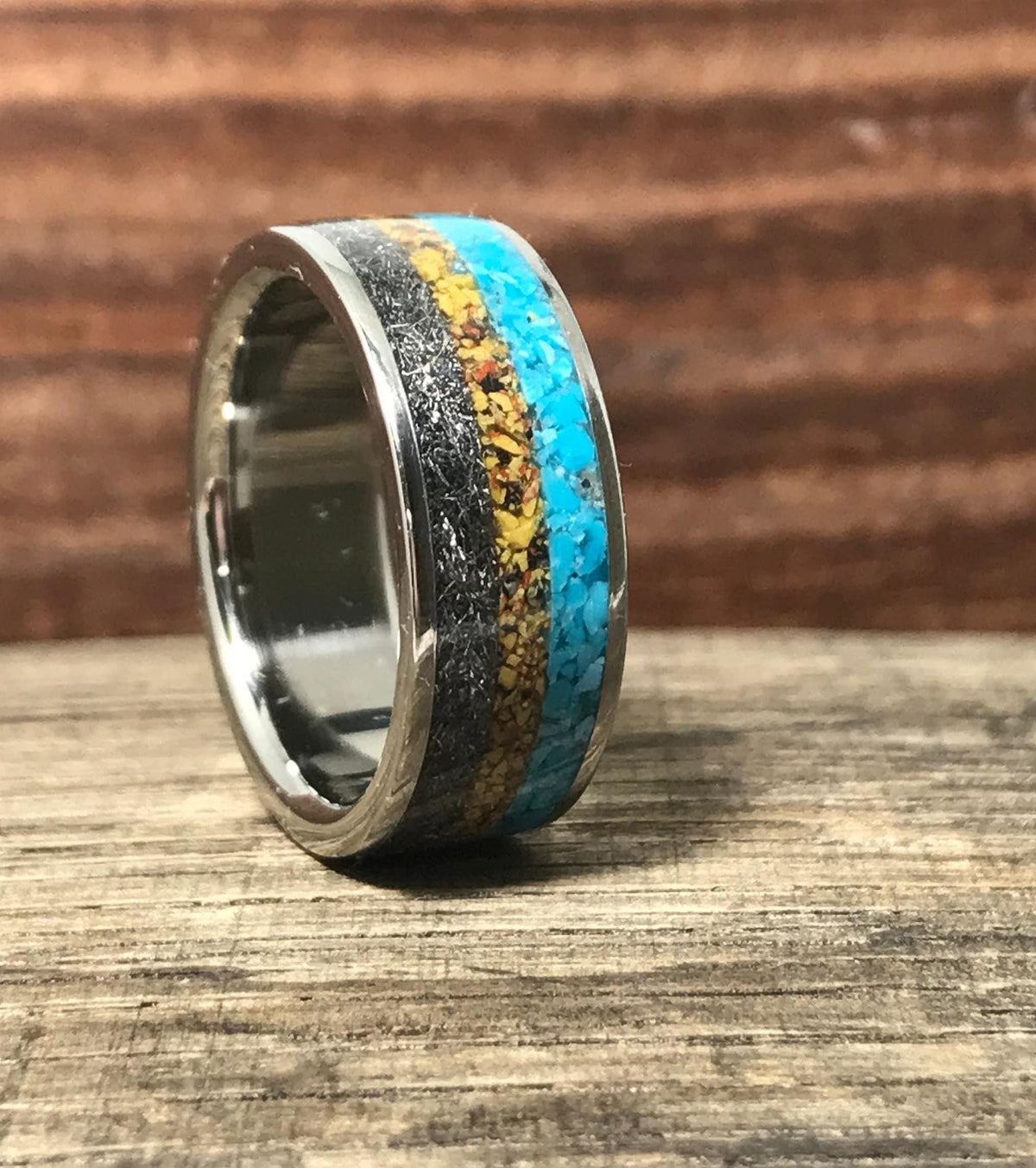 A side angle view of the ring highlighting the reflective metallic inner band and the textured inlay sections.
