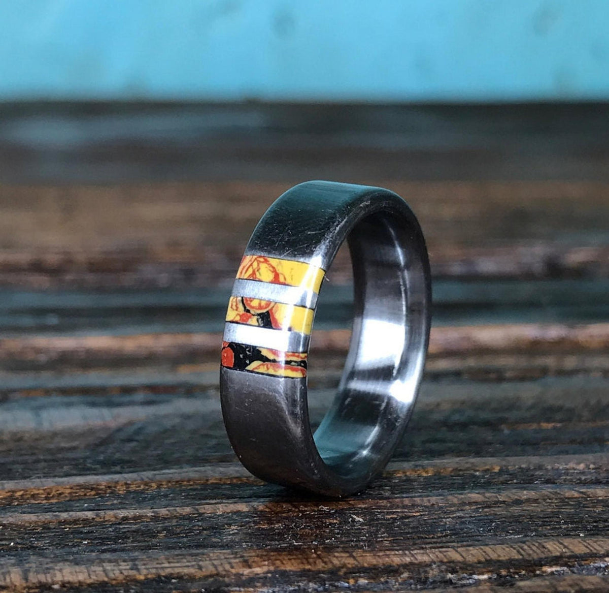 A slightly different angle of the metal ring standing on a dark wooden table against a blue background.