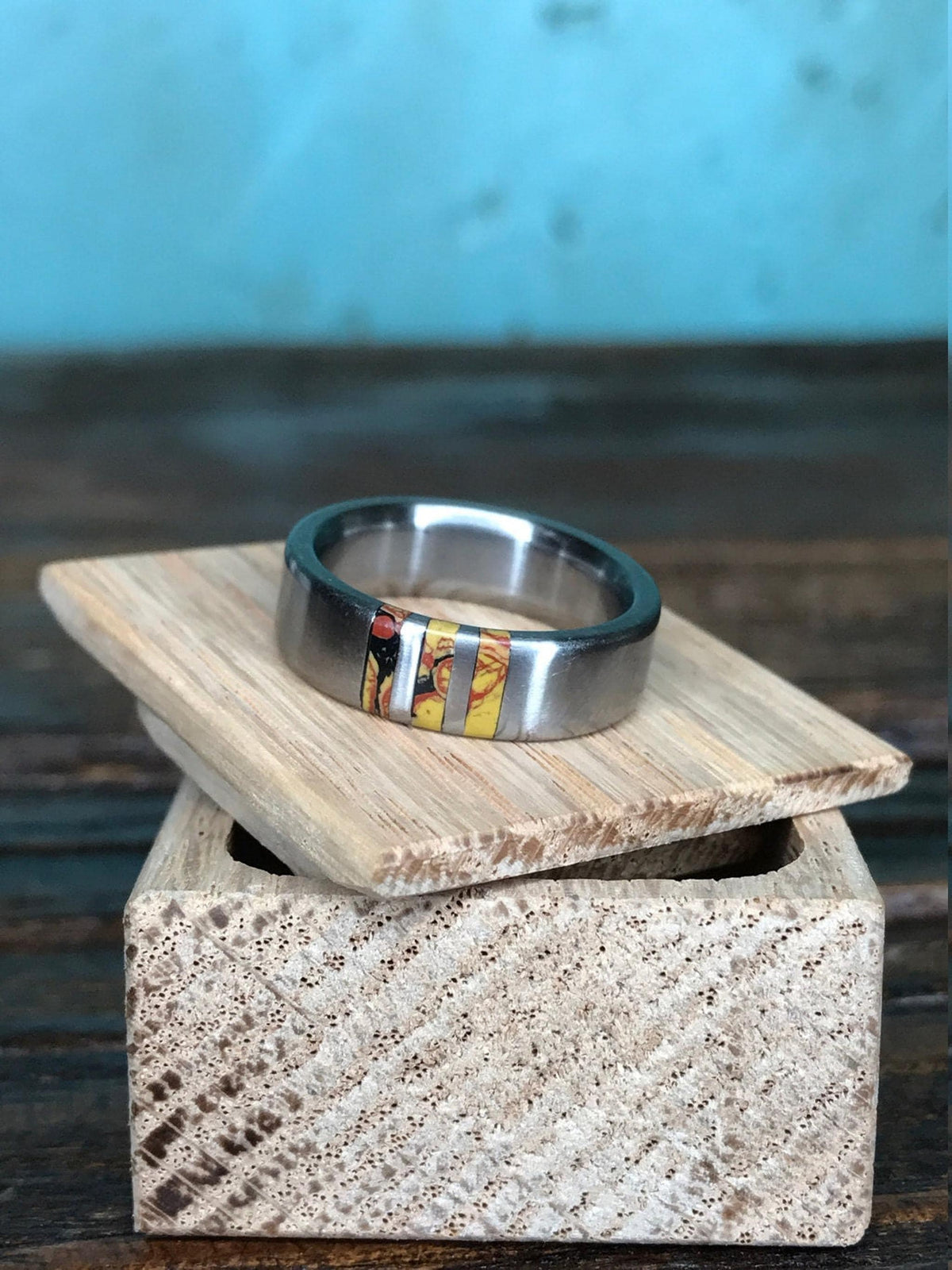 The ring rests atop a small wooden box with a textured exterior.