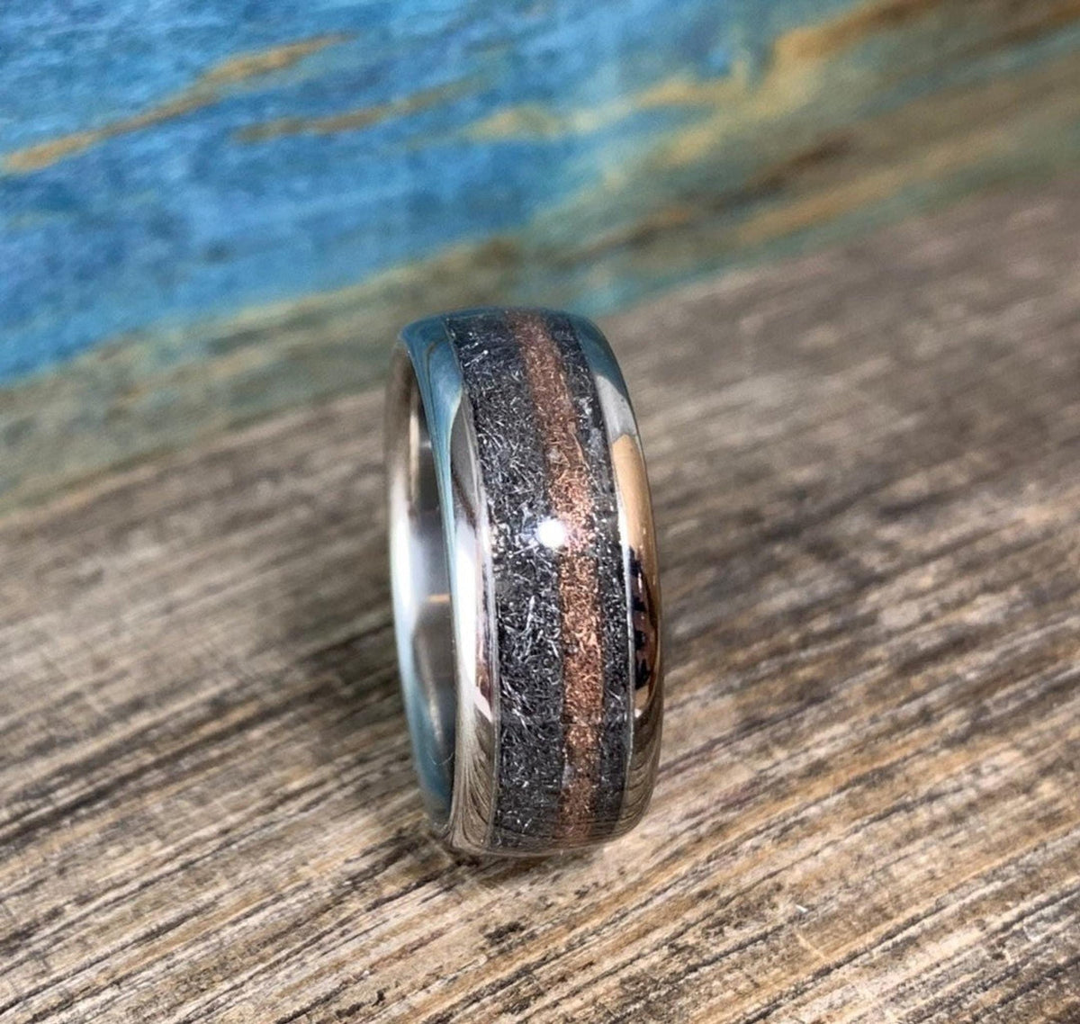 A close-up view of the titanium ring standing vertically, highlighting the detailed texture of the meteorite alongside the rose gold center line.
