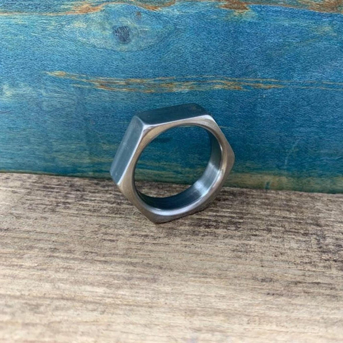 A side angle of the hexagonal wedding ring standing upright on wood.