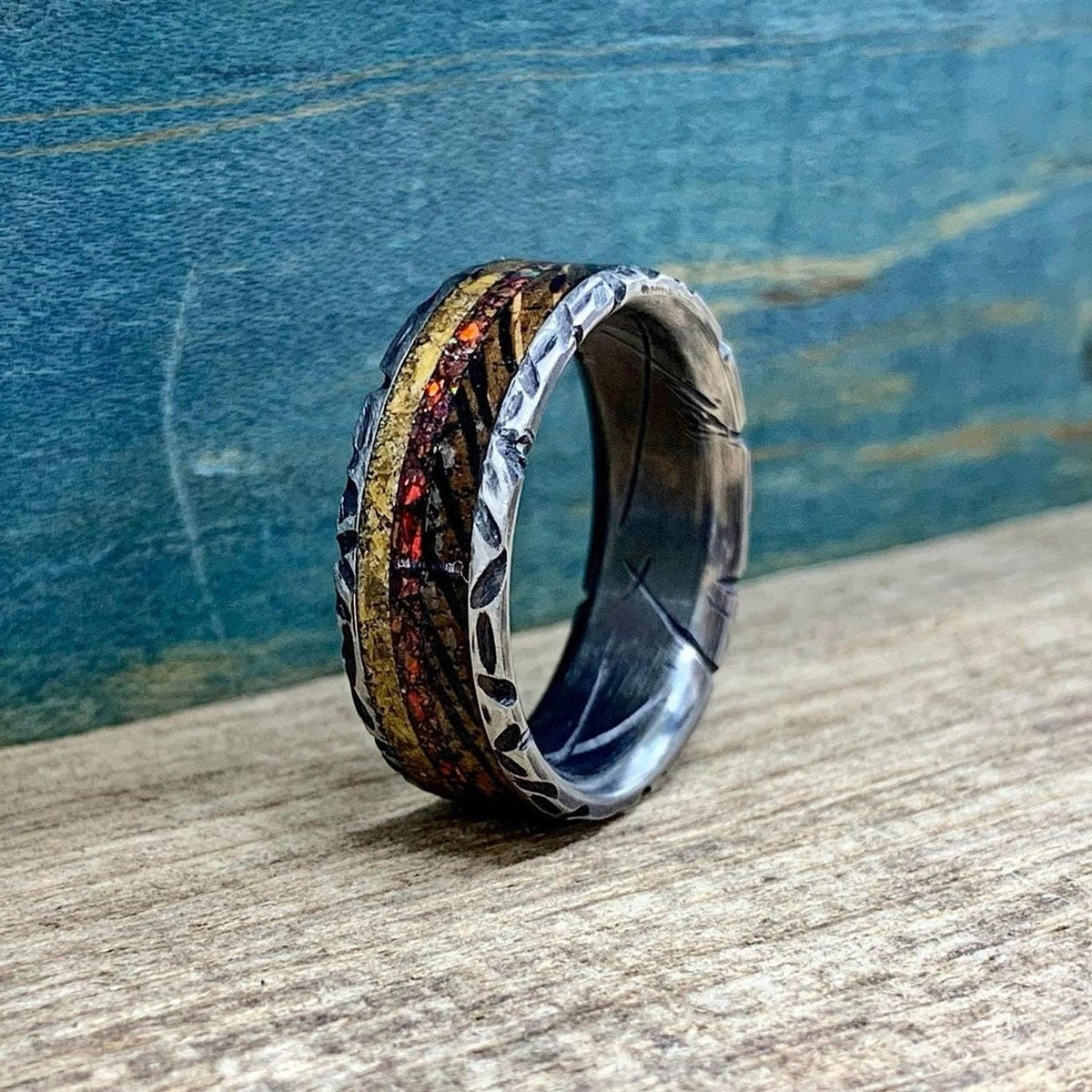 An angled view of the patterned wedding band showing the dark interior lining and multi-material inlay.