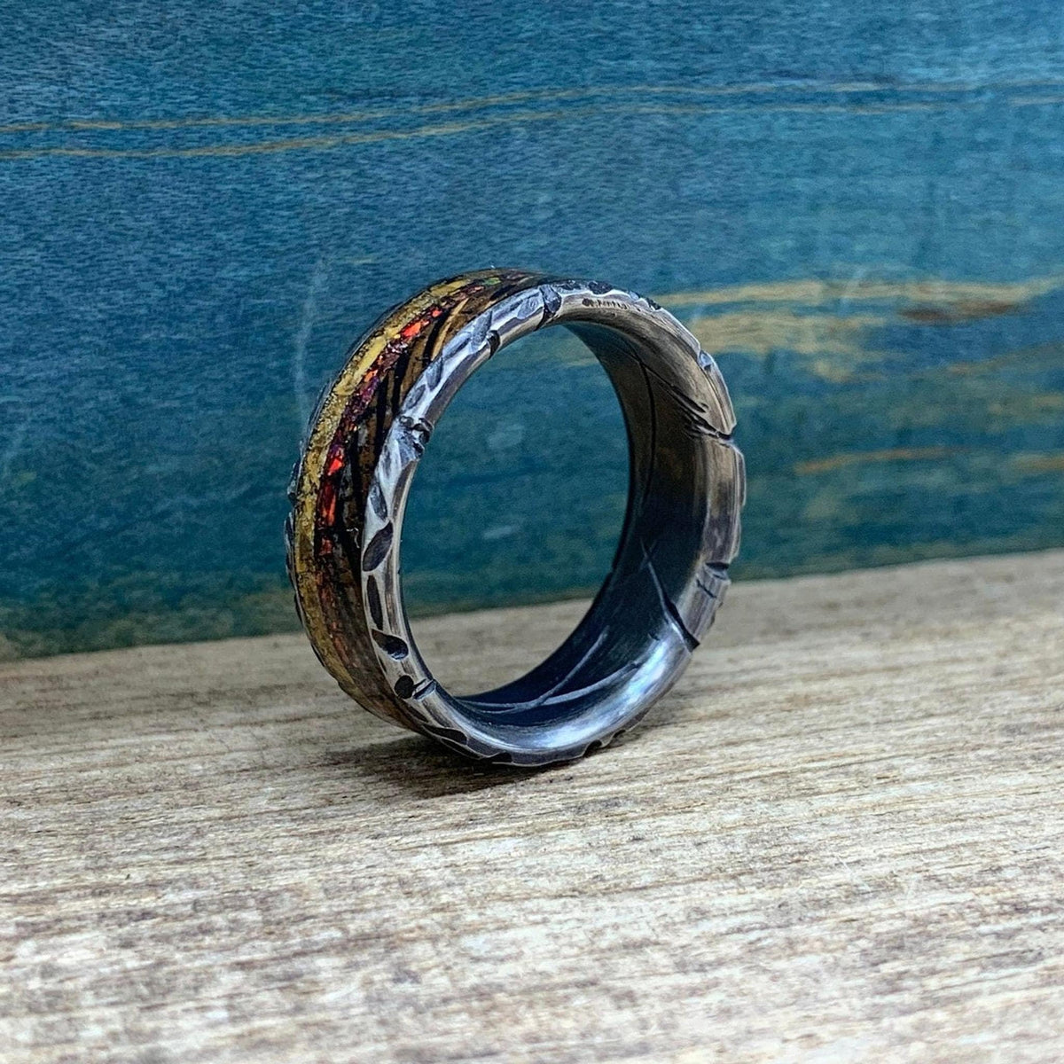 The patterned ring standing upright on a wooden surface, showing its hollow interior and dark carved edges.