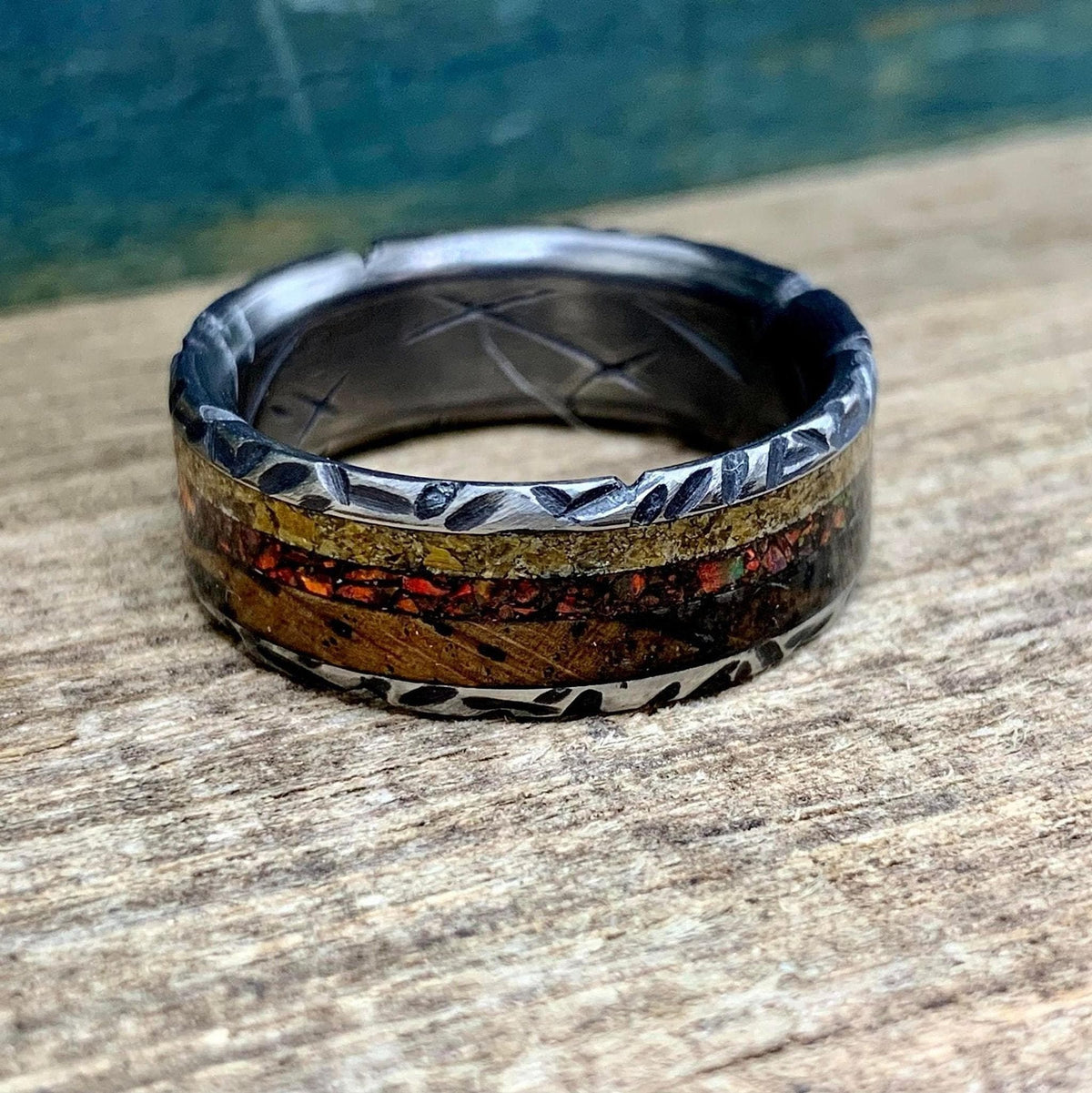 A macro shot of the ring focusing on the inlaid segments of wood, gold flakes, and red stone.