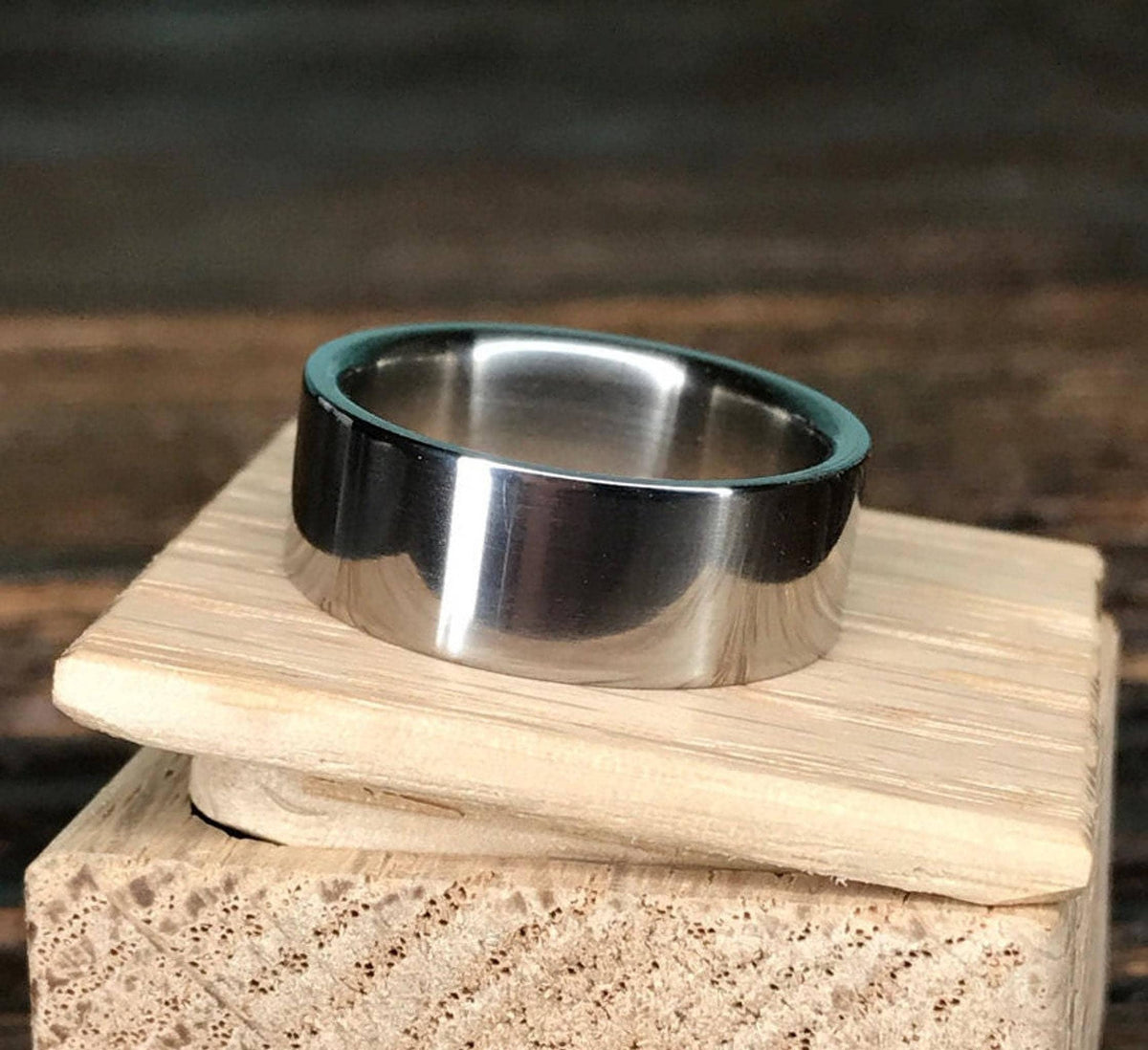 A polished metal ring rests on top of a small wooden block.