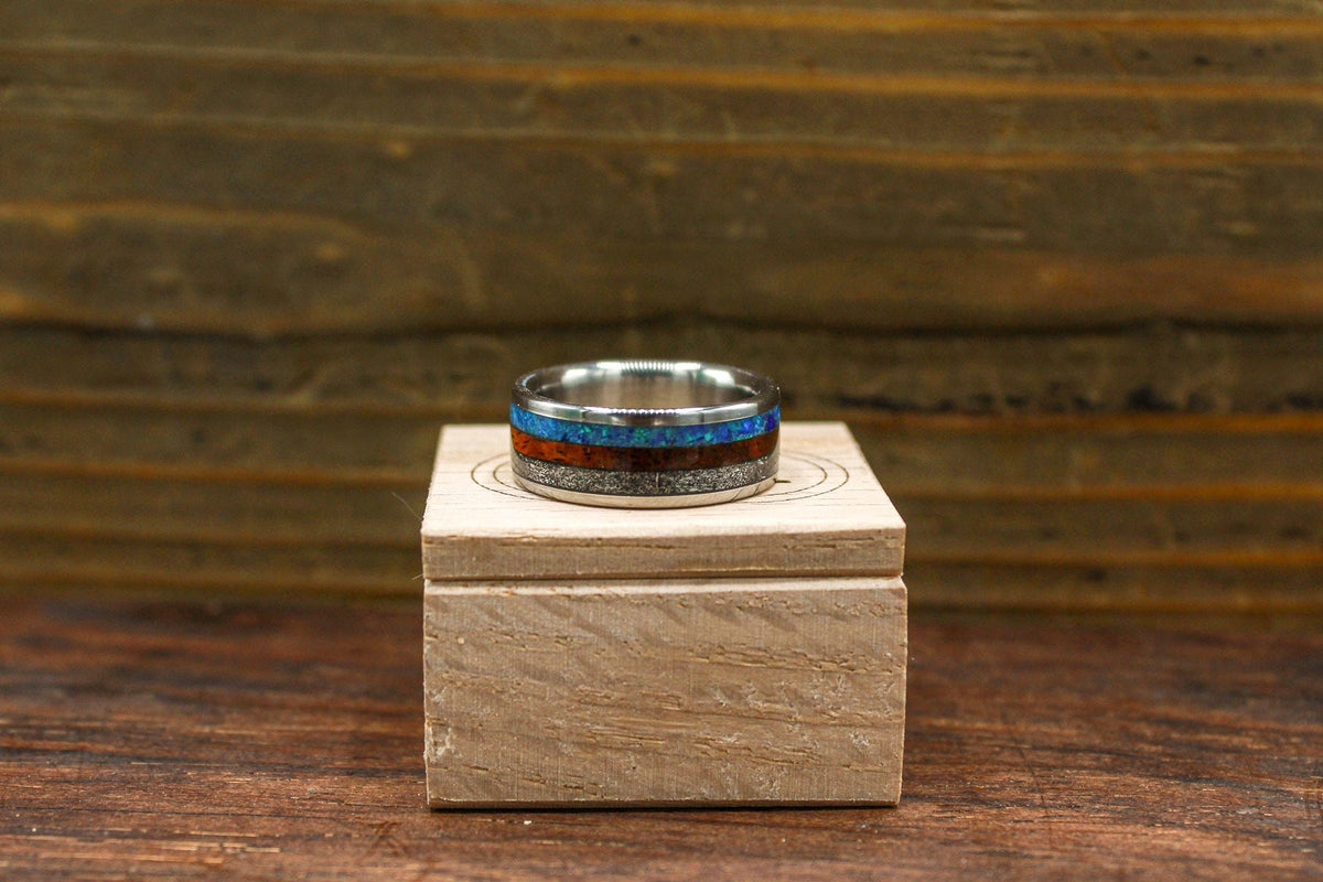 A straight-on view of the ring sitting upright on the engraved wooden box against a dark wooden backdrop.