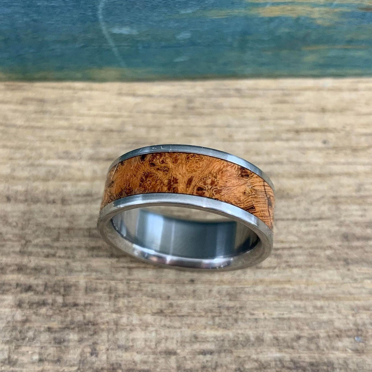 A silver metal ring featuring a textured brown wood inlay shown from a straight-on perspective.