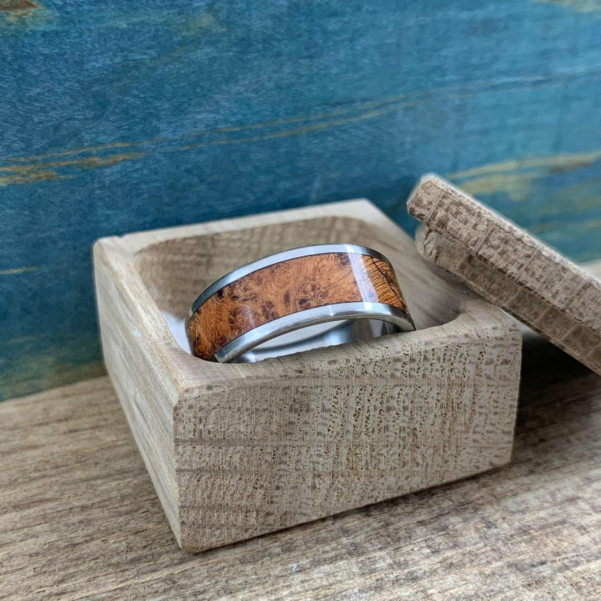 An angled view of the silver and wood ring sitting in a small wooden box.