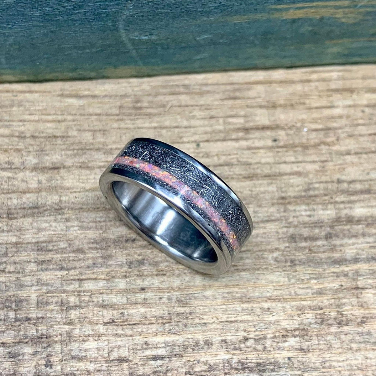 Lower angle shot of the ring showing the interplay of light on the central opal stripe and metallic meteorite pattern.