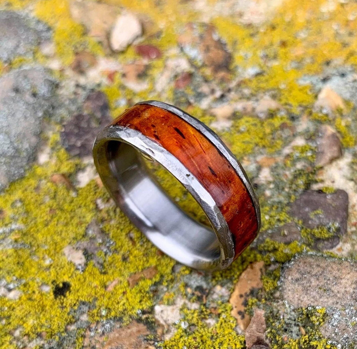 A detailed view of the ring angled on a rough, green-and-yellow mossy surface.