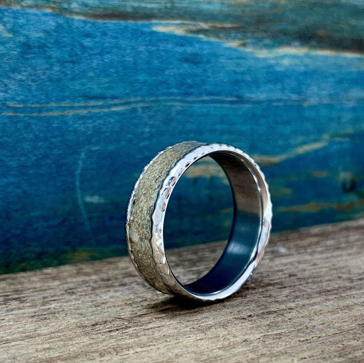 The ring positioned upright facing slightly left on a rustic wooden surface.