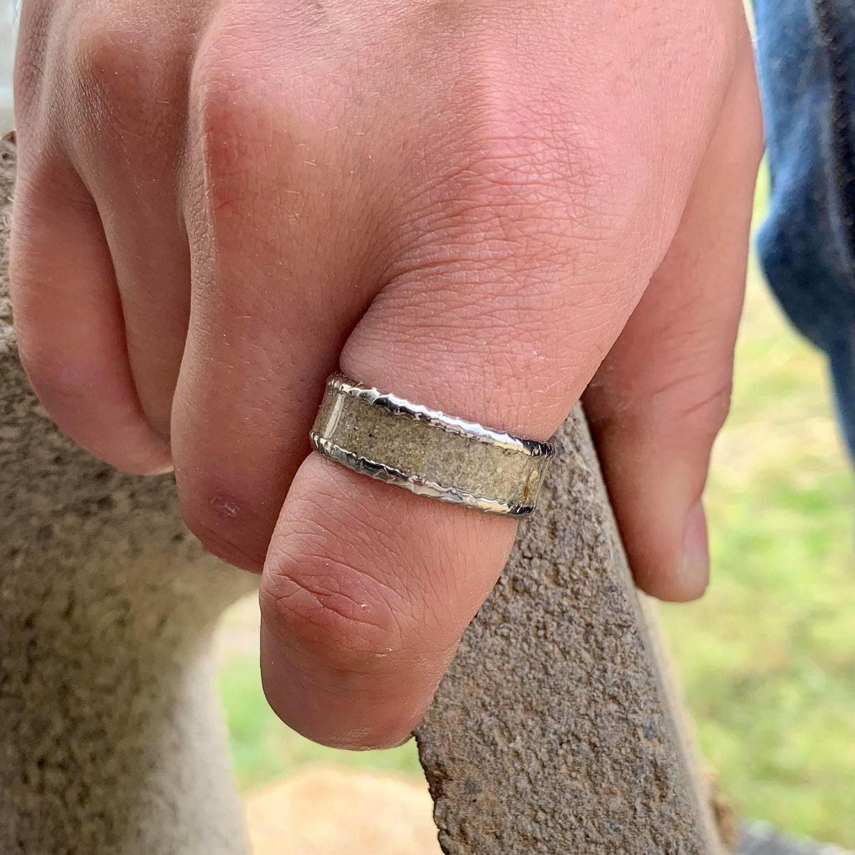 A hand wearing the titanium and concrete wedding band on the ring finger.