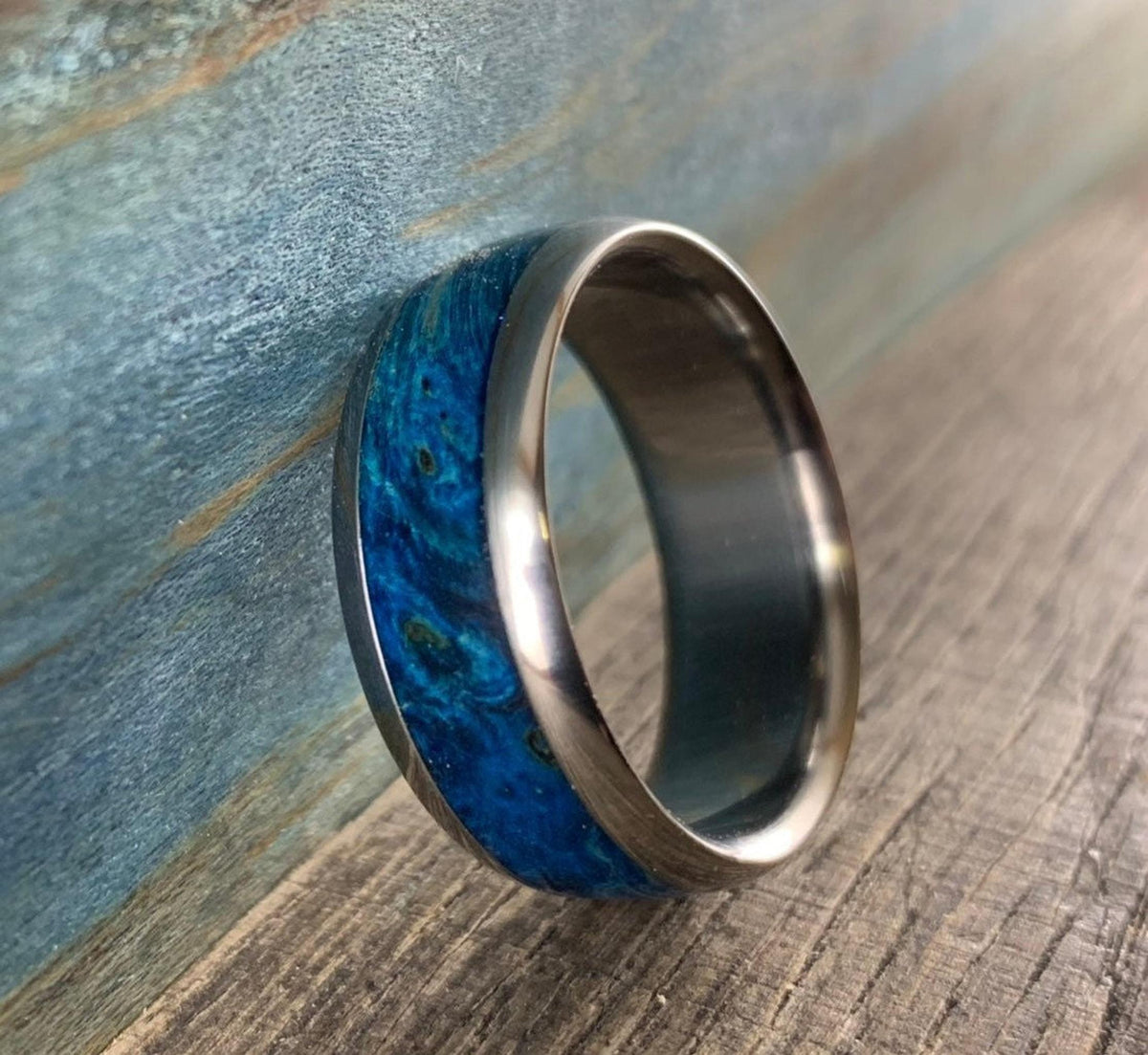 The ring stands upright against a weathered blue and brown wooden background.