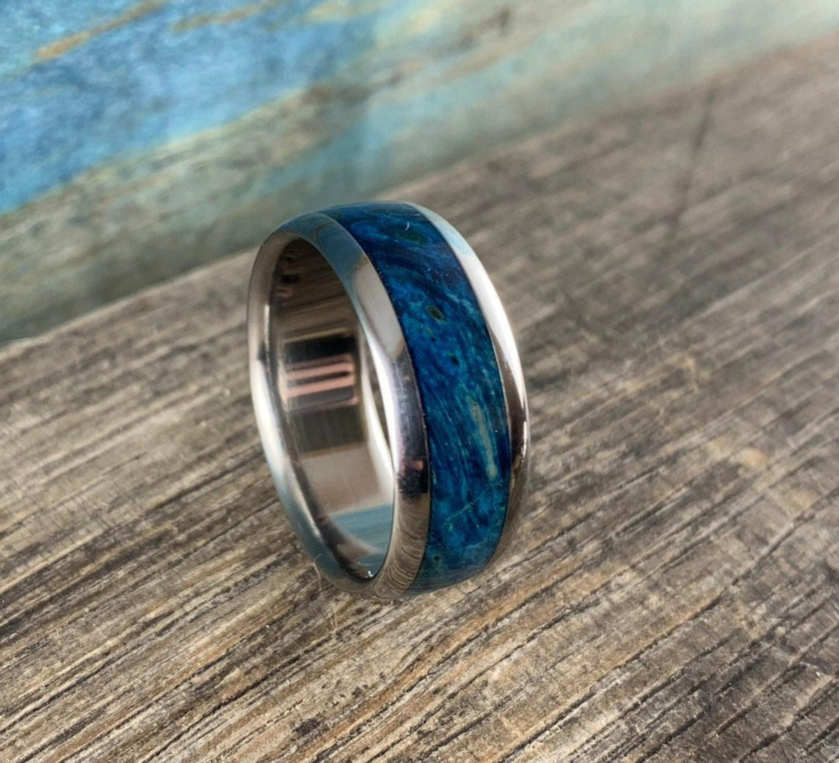 The ring is angled slightly to the left, showcasing its polished inner band and blue wood inlay.